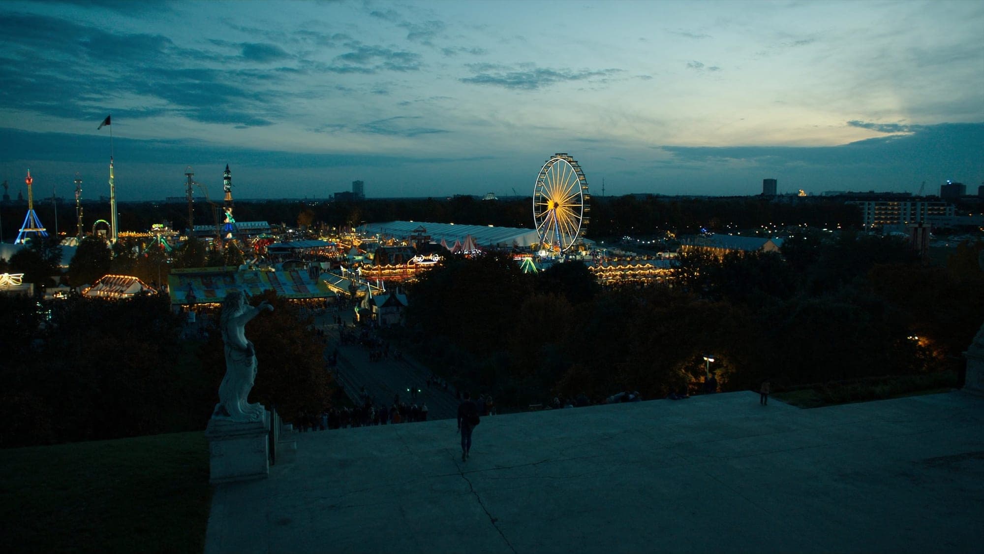Die Theresienwiese in München zur Oktoberfestzeit in der Abenddämmerung mit beleuchteten Fahrgeschäften