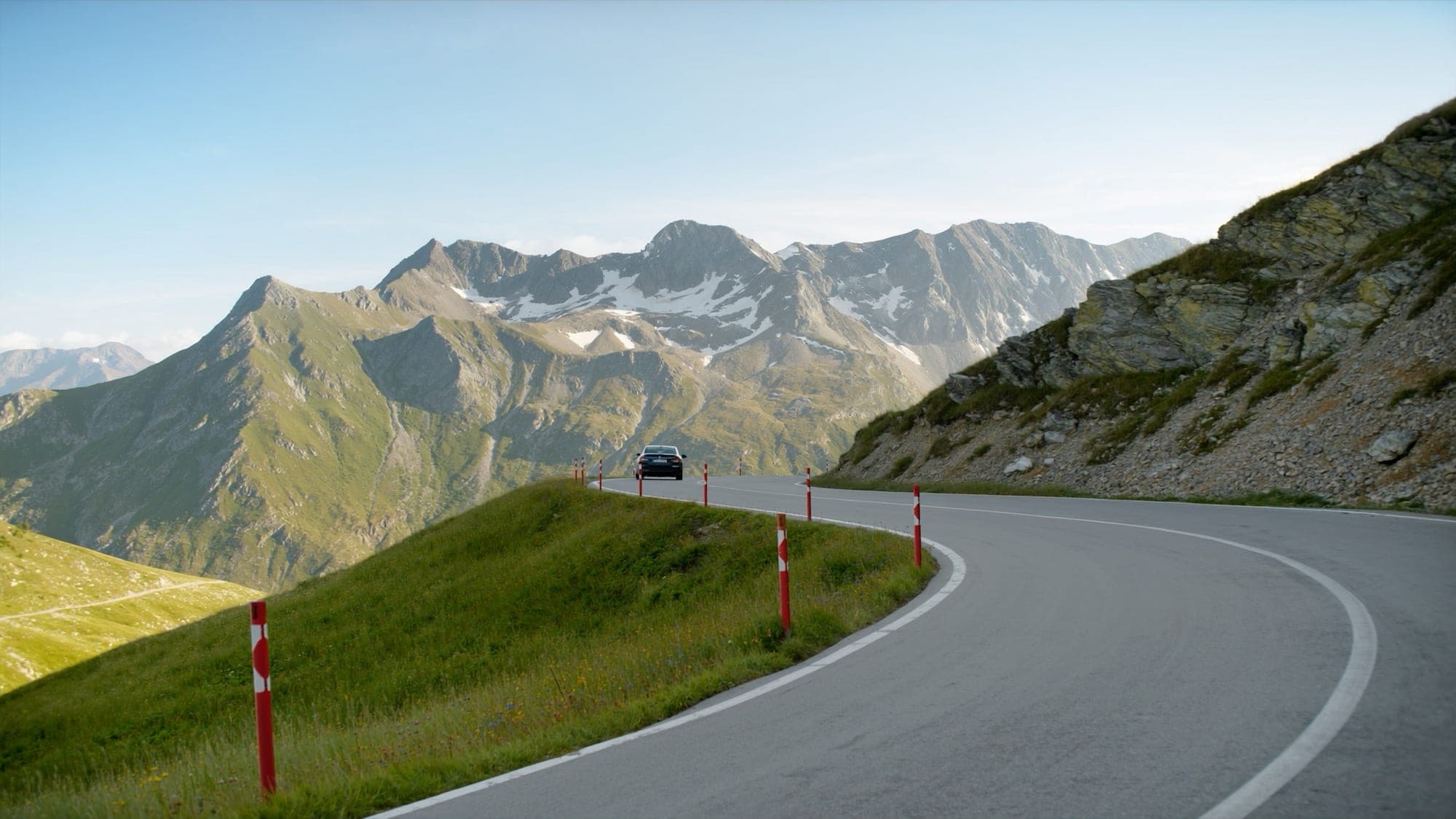 Die Arlberg-Passstraße bei St. Christoph an einem klaren Sommermorgen mit einer dunklen Limousine in der Kurve